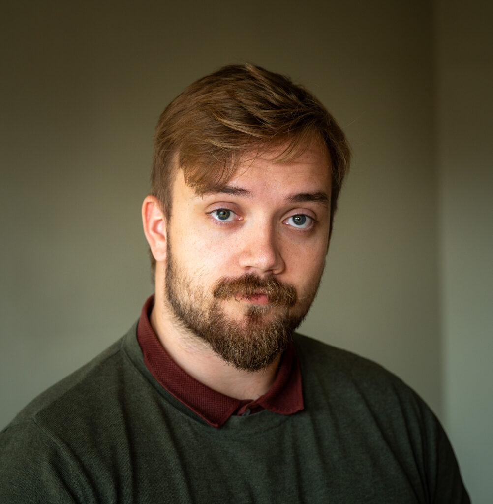 Portrett av Emil Olai Tødenes i grønn genser over ei mørkeraud skjorte.